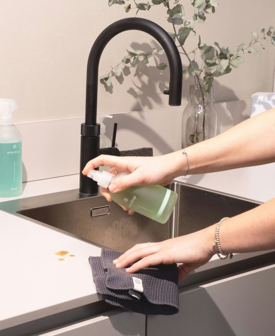 a woman is cleaning a kitchen sink with a rag