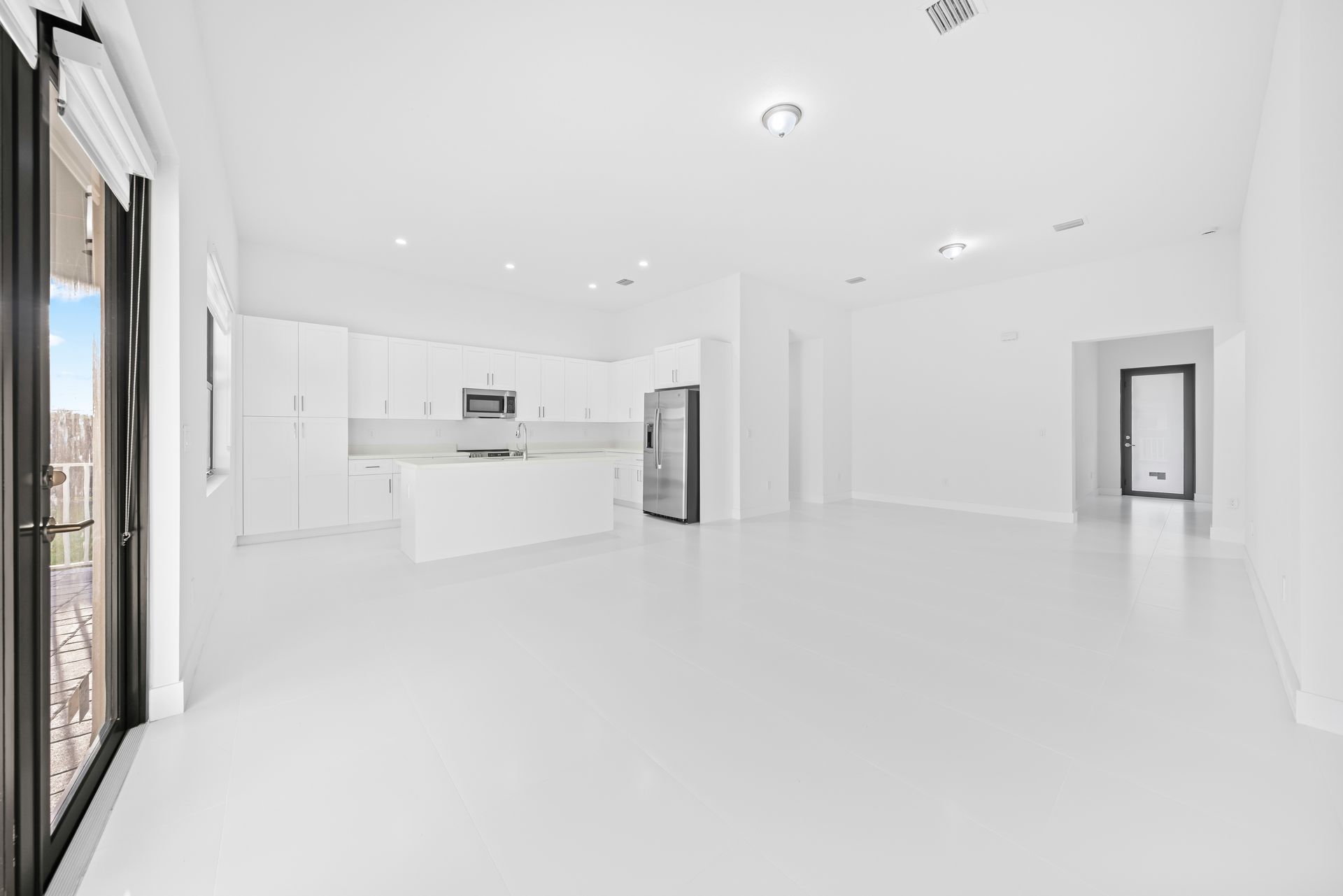Modern white kitchen and living area with large windows